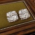 Primer plano de pendientes plateados con diseño de nudo en un joyero de terciopelo verde - Pin de acero inoxidable - Plateado