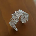 Silver vintage flower lace cuff bracelet with intricate metal filigree on wooden background - Silver