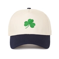 Close-up of the green clover embroidery and contrast stitching on a cotton baseball cap - Beige Crown + Navy Blue Brim