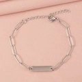 Close-up of a silver paperclip chain bracelet with a polished engravable bar on pink fabric - 1 Bar / Steel