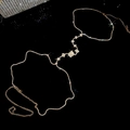 Dettaglio catena corpo in strass scintillanti con forme a diamante su specchio nero - Oro