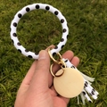Porte-clés bracelet en cuir PU à pois avec pompon et breloque en bois sur l'herbe - Blanc à pois noirs