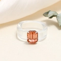 Macro shot of transparent resin ring featuring an amber square gemstone and claw setting - One Size / White