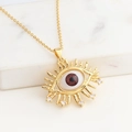 Detailaufnahme der Goldenen Evil Eye Halskette mit funkelnden Zirkon-Wimpern am Anhänger - Rot