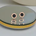Rose gold round stud earrings with Roman numerals and black inlay on mirror stand - Rose Gold Roman Stud Earrings