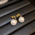 Macro shot of pearl stud earrings with golden base on a black textured jewelry tray - Real Gold Plated Silver Pin Round Pearl Studs