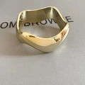 Macro-detail van een gegolfde gouden ring met gepolijste afwerking op een leren textuur - Golvende gepolijste gouden ring/armband (HB5033-2)