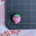 Macro d'une breloque fraise rose en résine montrant la taille de 1,5 cm sur un tapis - Mini / Fraise rose avec six points blancs