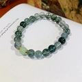 Detalle macro de cuentas de cuarzo fantasma verde y ojo de tigre sobre un libro abierto - Caja de Regalo Exquisita / Pulsera Fantasma Verde (Estilo Ágata Musgo)