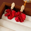 Detalle de pendientes de pétalos rojos con tachuelas doradas en joyero de lujo - Rojo