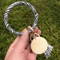 Close-up of zebra print PU leather bracelet with wooden charm and tassel on green grass - Zebra Print