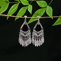 Detailed close-up of ethnic silver leaf tassel earrings hanging on a green branch - E4990-10 (Large Drop)