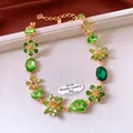 Dettaglio del pendente a fiore vintage in oro con cristalli verde smeraldo e diamanti - Oro-Verde