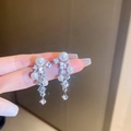 Primer plano de pendientes de borla con diamantes y grandes perlas blancas de moda - Estilo Plateado con Diamantes de Imitación y Perlas
