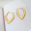 Macro detail of V-shaped 18K gold-plated titanium earrings with textured sunburst engraving - Striped Heart
