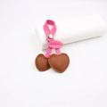 Close-up of heart-shaped cherry bag charm with pink leather stems and golden snap - Brown