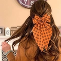 Große orangefarbene Haarschleife mit Sternmuster in braunem, gewelltem Haar - Federclip-Orange Schwarz Druck
