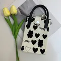 Detail of knitted phone bag with heart and bear patterns, black handle, and metal snap closure - Heart Beige-Happy/Lucky