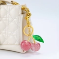 Detail of pink glitter cherry keychain pendant on a white quilted leather handbag - Pink Cherry with Leaf