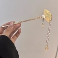 Golden fan-shaped hair pin with floral accents and long tassel charms in a hand-held view - F0522 Regular Style