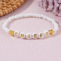 Pulsera de la amistad de cuentas blancas Chiefs con corazones dorados sobre fondo rosa - Corazón Letra CHIEFS