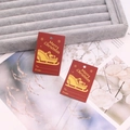 Macro shot of red Christmas gift tags with gold Merry Christmas print on grey tray - Red No.5 (Snowflake/Sleigh)