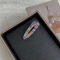 Dettaglio di fermagli per capelli marmorizzati con motivi viola e arancio in un vassoio - Conchiglia Iridata Cava Goccia