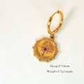 Detail of gold hoop earring featuring a starburst engraving and purple rhinestone inlay - Rose Zircon Star