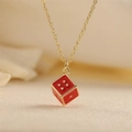 Golden necklace featuring a red enamel dice pendant with gold dots on a beige background - Red