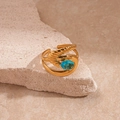 Macro shot of gold spiral ring featuring a central oval blue zircon on stone background - Gold Cross Texture