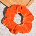 Close-up of bright orange velvet scrunchie with soft texture and elegant pleats - Orange