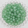 Detailed macro view of translucent green round glass beads stacked in a glass tray - 4mm / Verdant