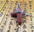 Detail of hexagonal natural stone pendants with silver metal clasps on a bamboo background - Gold Sandstone