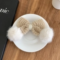 Barrette nœud en tricot beige avec pompons blancs sur une assiette blanche épurée - Kaki