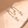 Detail van zilveren hangende oorbellen met kristallen en trapsgewijze witte parels - Geometrische Parel Hanger / Zilver