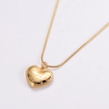 Makroaufnahme des goldenen Herzanhängers mit Gravur an einer glatten Schlangenkette - Gold
