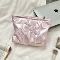 Detailed close-up of pink quilted makeup bag with bow patterns on a soft bed - Small Bow Pink