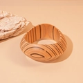 Detail view of natural wood bangle featuring unique grain texture and smooth finish - Coffee Patterned