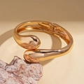 Primer plano detallado de un brazalete ancho de oro pulido sobre una base de piedra - Dorado