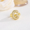 Macro di un anello dorato con lettera G incastonata con cristalli di zirconia cubica - Lettera G