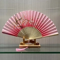 Chinese style folding fan with pink cherry blossom pattern and decorative tassel - Spring Breeze in the Hall (Pink)
