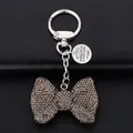 Sparkling rhinestone bow keychain with silver ring on black leather background - Gray