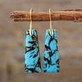 Detailed macro view of bohemian teal stone drop earrings hanging on a rustic wood branch - Blue Trapezoid
