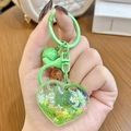 Green heart-shaped liquid quicksand keychain with stars and pearls in a hand - Green Heart Sparkle