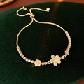 Detailed macro view of the gold flower and star charms with sparkling zircon on a bracelet - Gold