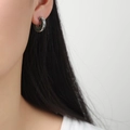 Elegant silver titanium C-shaped hoop earring with green crystals worn by model - Silver With Green Zircon