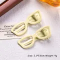 Detail of two cream-colored sunglasses-shaped hair clips with matte finish, size 2.1x5.8cm - Light Yellow