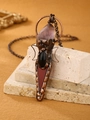 Detail of vintage bronze pendant featuring purple amethyst and ornate moon-like patterns - Rouge Red