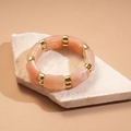 Détail du bracelet en résine pêche avec intercalaires dorés posé sur une pierre - Texture Marbre Rose (HB4173)