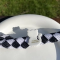 Détail de la pince à cheveux à carreaux avec pendentif chat blanc et texte doré élégant - Chat Blanc